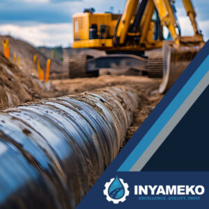 Construction site with a focus on large pipes being installed, and a yellow excavator in the background.